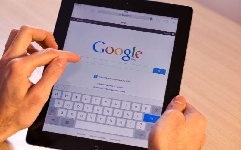 A person holding a tablet with the google logo on it while using SEO Services.