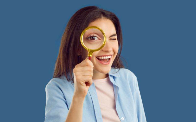 A woman examining dental SEO services through a magnifying glass.