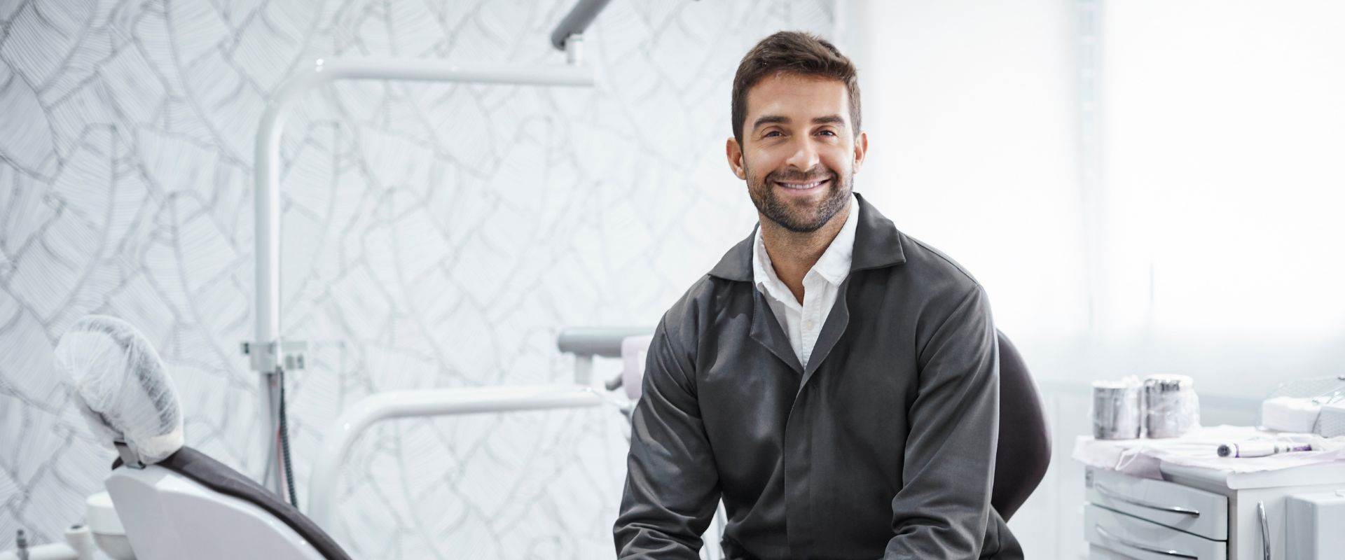 Smiling male dentist in a modern dental office, showcasing professionalism and expertise in dental care.