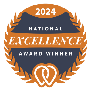 2024 National Excellence Award Winner badge, featuring an orange laurel wreath, navy blue background, and white and orange text with a heart symbol at the bottom.