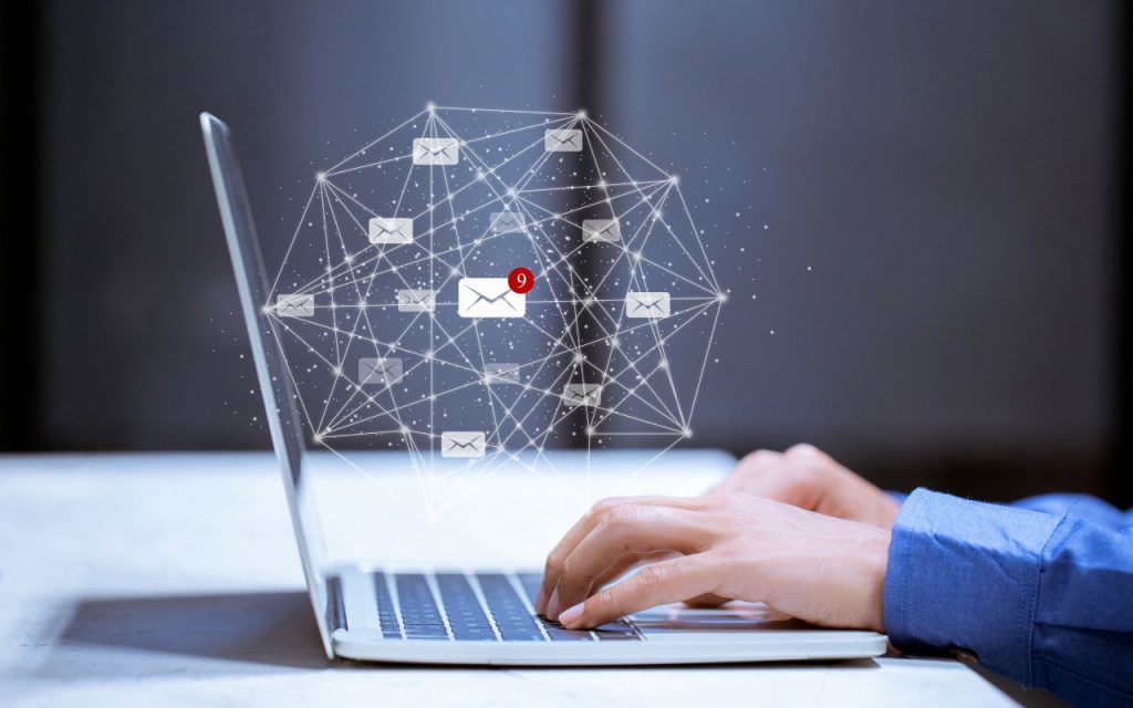 Person typing on a laptop with a digital overlay showing email icons connected by lines, one email notification marked with the number nine.